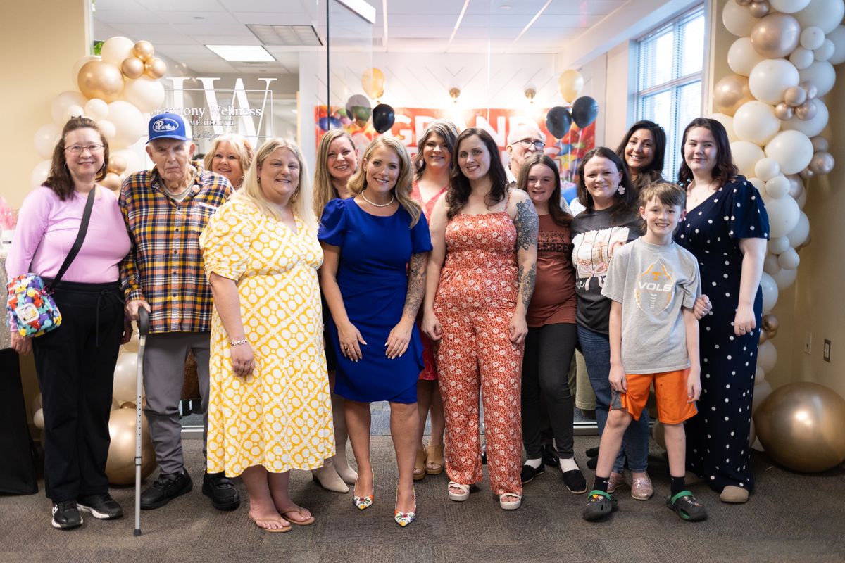 Group photo in front of balloon arch at Grand Opening